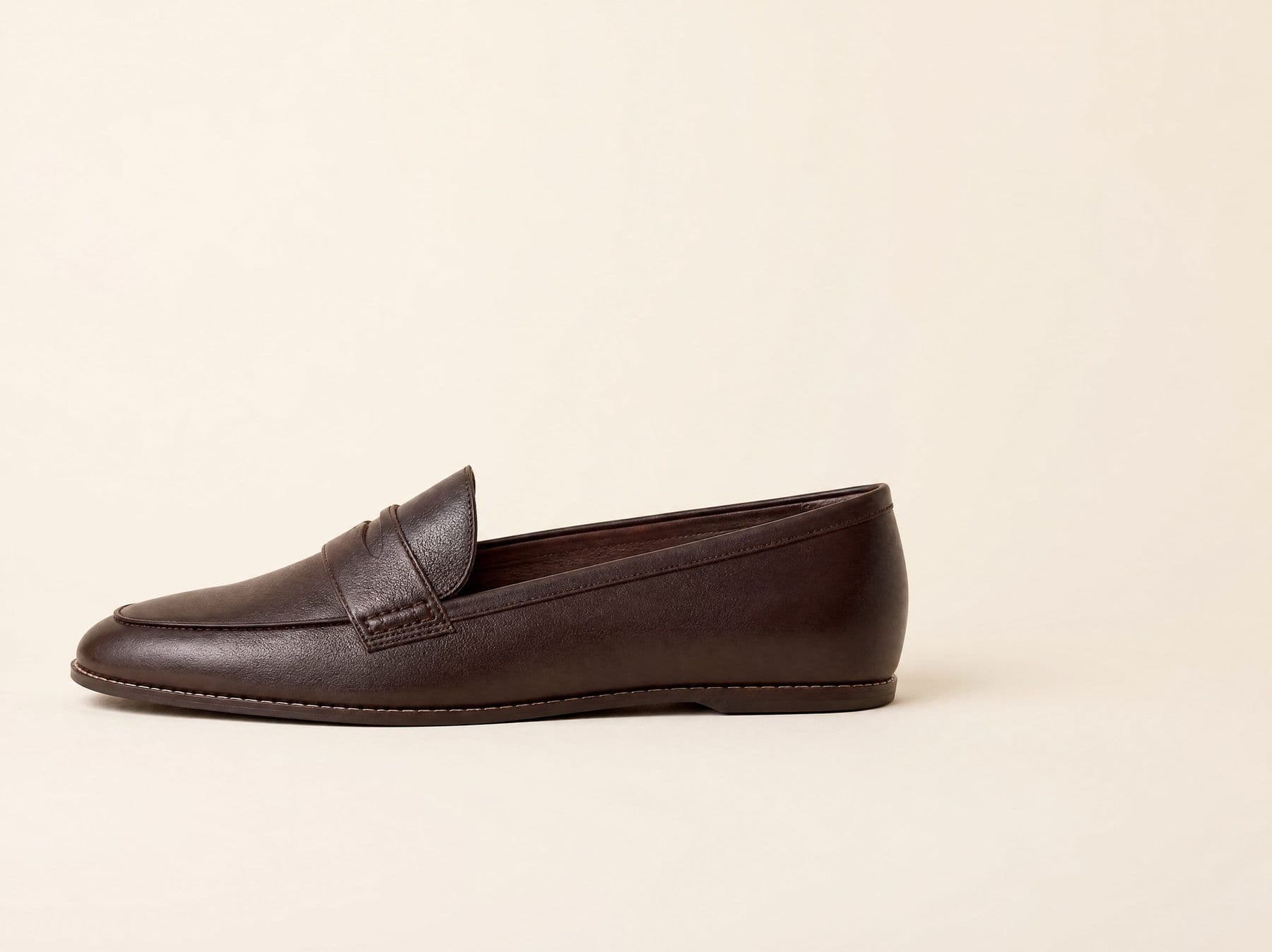 A Lofra loafer photographed from the side against an almond background, with the insole visible through the throat.